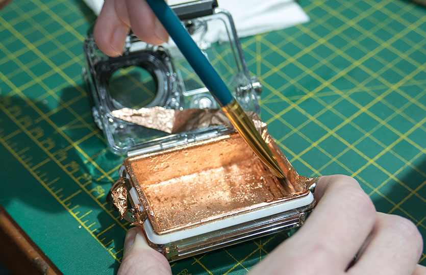 Applying the copper leaf to the back panel on the waterproof case